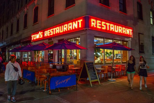 outside tom's restaurant with neon sign lit at night